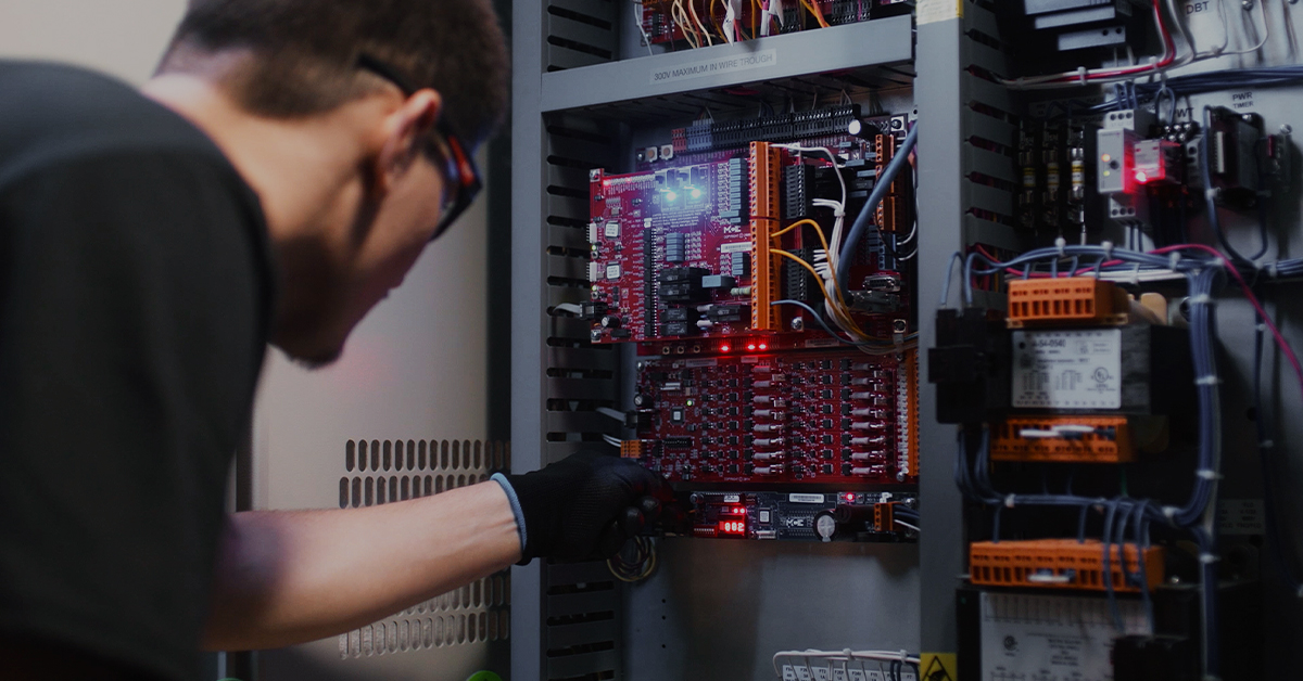 Door Lock 2 A focused technician troubleshooting an elevator's red control board with LED indicators.