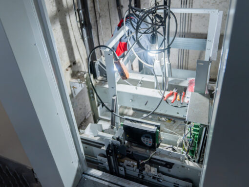 Interior view of an elevator shaft showing complex wiring and mechanical parts during maintenance.