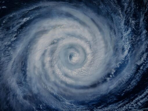 Satellite view of a large hurricane forming over the ocean, with a visible eye and swirling cloud bands.
