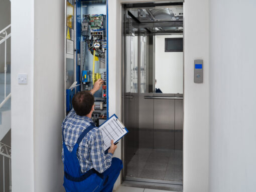 A technician with a clipboard inspects and tests an elevator control panel next to an open elevator car.